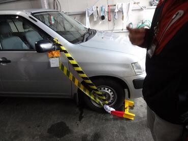 写真:車のドアミラーとタイヤをトラテープで繋いでロック装置が付けられた様子
