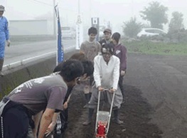 写真:大豆の種をまく常葉大生
