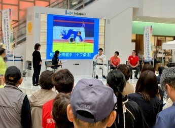 ステージイベントの様子（左から手話通訳、アナウンサー、佐藤選手、高橋選手、早瀬選手。佐藤選手がインタビューに答えている場面）
