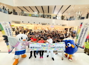 ステージイベント集合写真（左からゆりーと、早瀬選手、高橋選手、佐藤選手、アナウンサー、ふじっぴー、後ろに観客の皆さん。全員で手話のデフリンピックポーズ）
