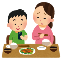 食事中にスマホに熱中する男の子と母親