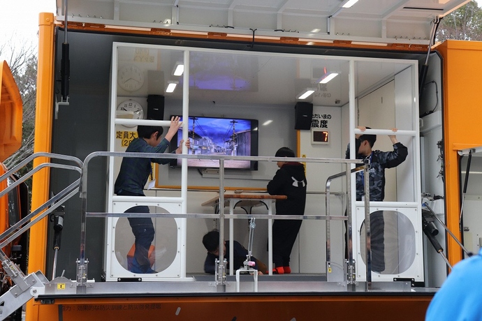 地震体験車で地震の揺れを体験している写真